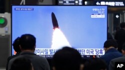 Orang-orang menonton TV yang menampilkan gambar peluncuran rudal Korea Utara dalam program berita di Stasiun Kereta Api Suseo di Seoul, Korea Selatan, Kamis. 25 Maret 2021. (Foto: AP)