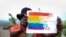 FILE - A gay Ugandan man holds a pride sign as he poses for a photograph in Uganda Saturday, March 25, 2023.