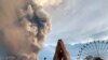 People watch as the Taal volcano spews ash and smoke during an eruption in Tagaytay, Cavite province south of Manila, Philippines.