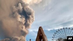 People watch as the Taal volcano spews ash and smoke during an eruption in Tagaytay, Cavite province south of Manila, Philippines.