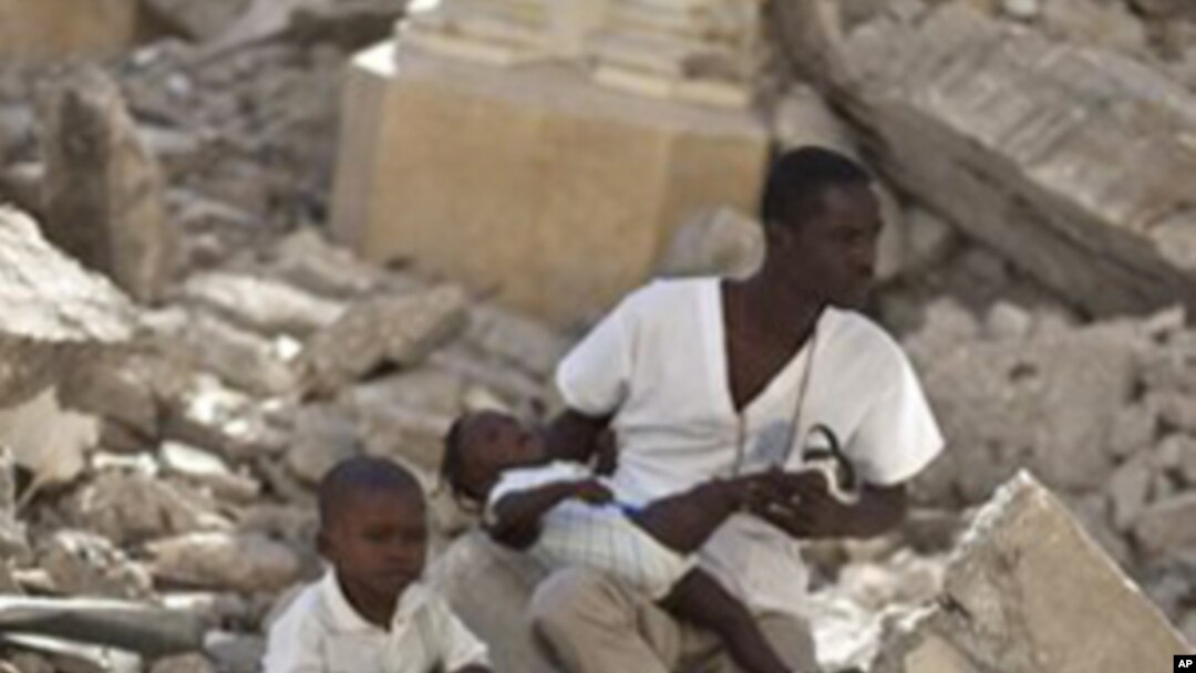 A man with two children sits in the rubble of the earthquake-damaged Cathedral during a mass in Port-au-Prince, Haiti, Jan. 12, 2011.