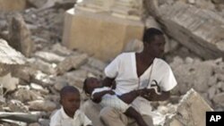A man with two children sits in the rubble of the earthquake-damaged Cathedral during a mass in Port-au-Prince, Haiti, Jan. 12, 2011.