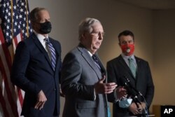 Senate Majority Leader Mitch McConnell, R-Ky., flanked by Sen. John Thune, R-S.D., left, and Sen. Todd Young, R-Ind., talks to reporters on Capitol Hill in Washington, Nov. 17, 2020.