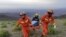 This May 22, 2021, photo shows rescuers carrying equipment as they search for runners who were competing in a 100-kilometer cross-country mountain race when extreme weather hit the area, leaving at least 21 dead, near the city of Baiyin, China. 