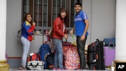 Migrantes venezolanos aguardan frente a la embajada de supaís en Lima, Perú, un autobús que los llevará al aeropuerto el lunes, 27 de agosto de 2018.