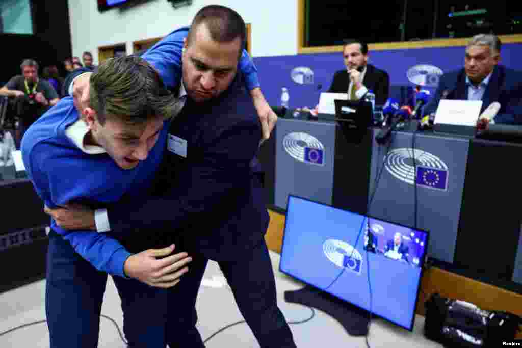 A security member grabs a protester as Hungarian Prime Minister Viktor Orban speaks during a press conference with MEP Kinga Gal, Vice-President of Patriots for Europe Group, at the European Parliament in Strasbourg, France.