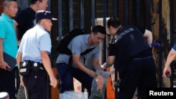 Personal de seguridad e investigadores trabajan afuera de la Embajada de EE.UU. en Beijing, luego de una explosión en el lugar. Julio 26, 2018.