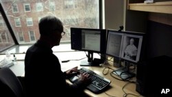 Brown University professor David Kertzer sorts through documents on his computer, including a photo of Pope Pius IX, in his office on the Brown campus in Providence, April 17, 2018.