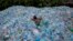 A worker uses a rope to move through a pile of empty plastic bottles at a recycling workshop in Mumbai, June 5, 2014. Plastic bottles are one of the everyday items that contain endocrine-disruptors.
