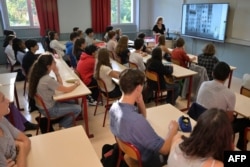 FILE - Students listen to their teacher in a classroom of Victor-Duruy high school on the first day of new academic year in Paris, France, Sept. 4, 2023.