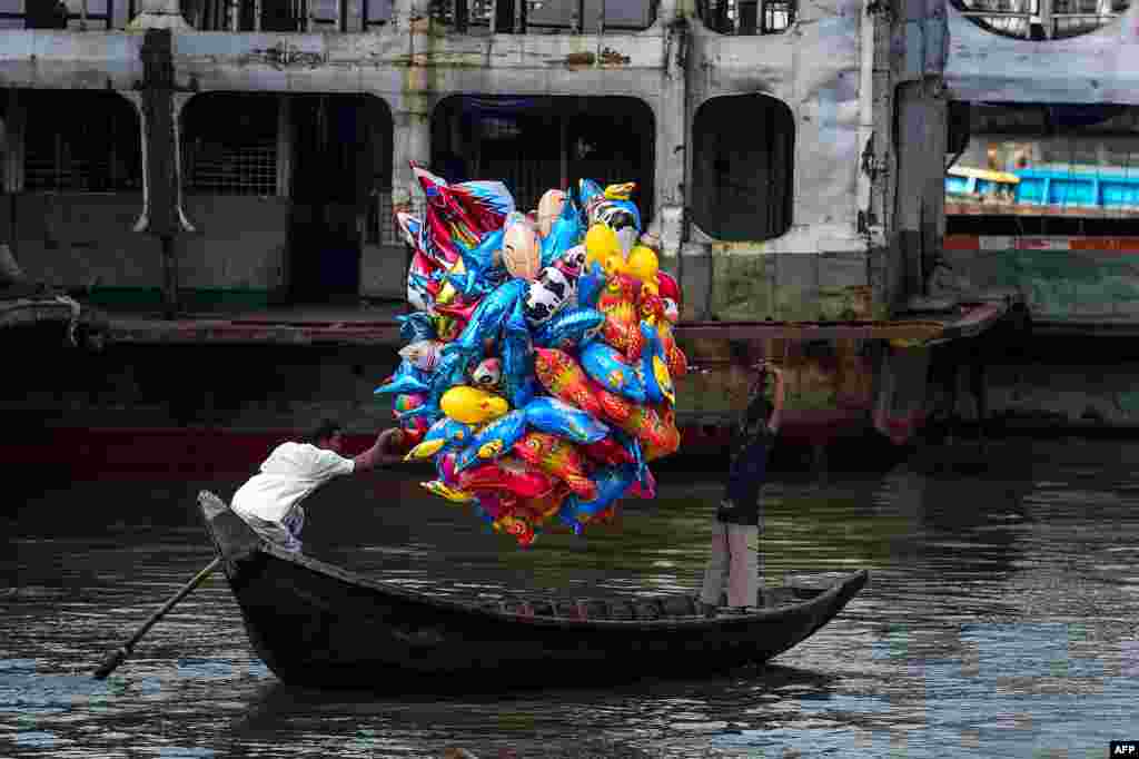 A man holds balloons as he crosses the Buriganga River on a boat in Dhaka, Bangladesh.