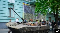 人们在观看被运到基辅展示的一辆被乌军摧毁的俄军装甲车。(2022年5月12日)