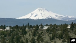 Mount Jefferson looms over off-grid homes at the Three Rivers Recreational Area, in Lake Billy Chinook, Ore., on April 26, 2007. Everyone in this community lives "off the grid", part of a growing number of homeowners now drawing all their power from solar, wind, propane and other sources. (AP Photo/Don Ryan, File)