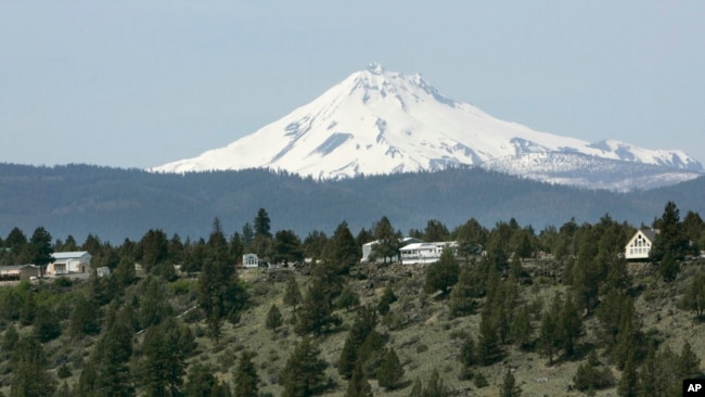 Mount Jefferson looms over off-grid homes at the Three Rivers Recreational Area, in Lake Billy Chinook, Ore., on April 26, 2007. Everyone in this community lives "off the grid", part of a growing number of homeowners now drawing all their power from solar, wind, propane and other sources. (AP Photo/Don Ryan, File)