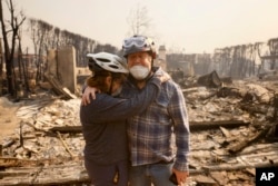 Claudio and Kathleen Boltiansky embrace in their fire-ravaged neighborhood after the Palisades Fire swept through the Pacific Palisades area of Los Angeles, Jan. 8, 2025.