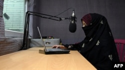 FILE - A radio presenter reads the news during a broadcast at the Merman radio station in Kandahar, Sept. 29, 2020.