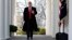 FILE - President Donald Trump waves as he walks through the Colonnade from the Oval Office of the White House on arrival to make an announcement.