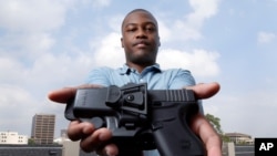 Charles Blain, a new gun owner, poses with his holstered 9mm Glock 43 handgun, May 3, 2021, on the parking garage of his apartment complex in Houston. Blain also owns a shotgun.