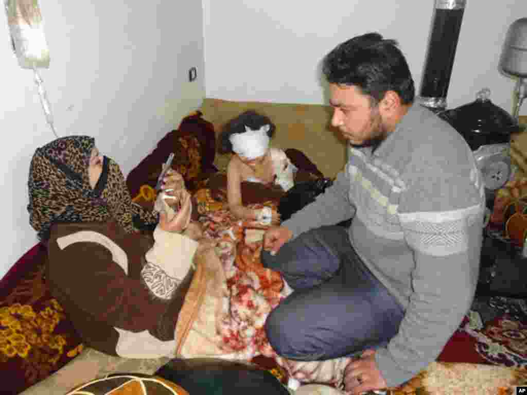 A girl wounded February 5, 2012, sits next to her relatives in a neighbourhood of Homs February 6, 2012. (Reuters)