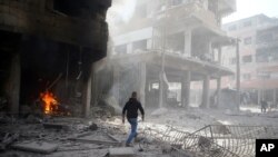 A man walks on rubble at a damaged site after an airstrike in the besieged town of Douma, Eastern Ghouta, Damascus, Syria, Feb. 9, 2018. 