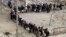 Rebel fighters queue as they wait to be evacuated from the Old City of Homs, May 8, 2014. 