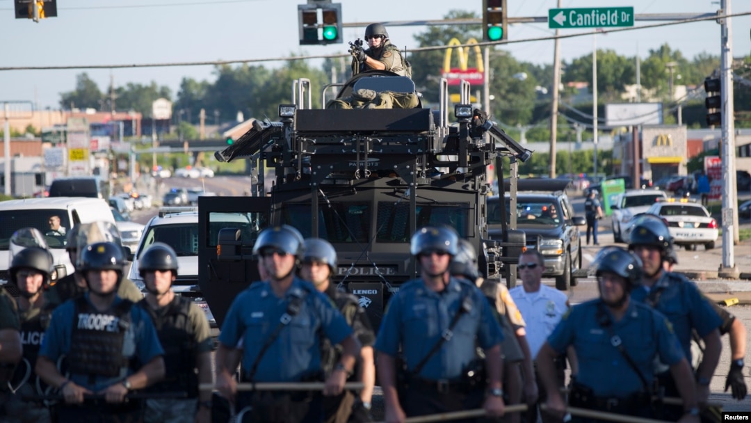 Riot police stand guard as demonstrators protest the shooting death of teenager Michael Brown in Ferguson, Missouri August 13, 2014.