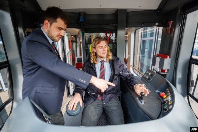 FILE - Christopher Hecht instructs Benedikt Hanne, a social work student at a university, in driving streetcars in Nuremberg, southern Germany, on March 21, 2024. . Nuremberg, Germany's city services is looking to expand its worker pool. (Daniel Karmann / AFP)