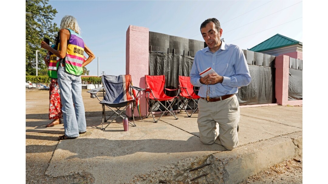 A man recites the rosary outside the Jackson Women's Health Organization clinic, while clinic escorts wait for incoming patients in Jackson, Mississippi, Oct. 2, 2019.