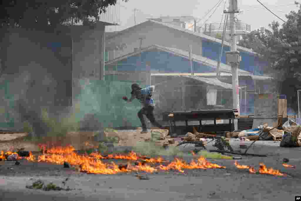 쿠데타 반대 시위가 계속되고 있는 미얀마 만달레이에서 한 남성이 불에 타고 있는 잔해 뒤로 뛰어가고 있다. 