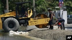 Workers fix the entrance to an air force cadet school near Don Muang airport as flood waters approach Tuesday, Oct. 25, 2011 in Bangkok, Thailand.