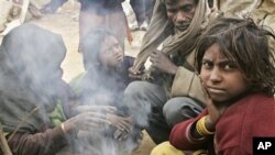 A family of workers sits near a kitchen fire at a makeshift shelter near a construction site, in Gurgaon, India, (file photo)