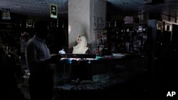 A Bangladeshi customer walks past a salesgirl in a shopping mall during a blackout in Dhaka, Nov. 1, 2014. 