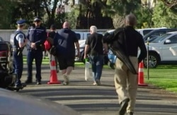 In this image made from video, people bring their guns to exchange for money in Christchurch, New Zealand, July 13, 2019.
