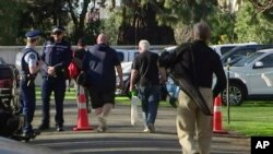 In this image made from video, people bring their guns to exchange for money in Christchurch, New Zealand Saturday, July 13, 2019.