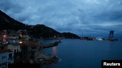 The capsized cruise liner Costa Concordia lies surrounded by cranes outside Giglio harbor, Italy, Jan. 13, 2013.