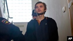FILE - Blogger Ruslan Sokolovsky is escorted by police officers in a court building in Yekaterinburg, Russia.