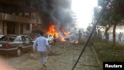 Seorang pria berjalan di dekat mobil yang terbakar pasca ledakan di dekat Kedutaan Iran di Beirut (19/11).