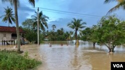 ទឹកហូរ​ចូល​ផ្ទះមួយខ្នង​របស់​​អ្នកភូមិ​ ក្រោយការ​បាក់​ទំនប់​អាងទឹក​មួយដោយសារភ្លៀងធ្លាក់ខ្លាំង ​ក្នុង​ស្រុក​ទឹក​ឈូ​ ខេត្ត​កំពត​ ថ្ងៃទី​១១ ខែ​សីហា​ ឆ្នាំ​ ២០១៩​។ (ហ៊ុល រស្មី​/VOA)