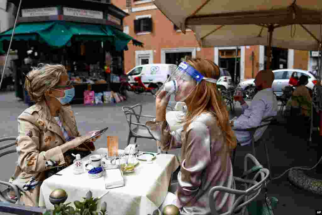 A woman sips her coffee at a cafe in Rome, Italy. Italy is slowly lifting restrictions after a two-month coronavirus lockdown.