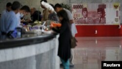 FILE - Customers are seen at a counter inside the Bank Indonesia complex in Jakarta, Indonesia, Dec. 16, 2015. 