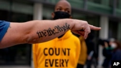 The tattoo "We The People", a phrase from the U.S. Constitution, decorates the arm of a Trump supporter as he argues with counterprotester Ralph Gaines outside the central counting board at the TCF Center in Detroit, Nov. 5, 2020.