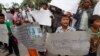 FILE - A boy holds a banner reading "Please stop grabbing our land" at a rally by land eviction victims in front of the National Assembly in Phnom Penh, Cambodia, Sept. 1, 2014.