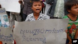 Một cậu bé cầm biểu ngữ 'Hãy ngưng lấy đất của chúng tôi' tại một cuộc biểu tình của các nạn nhân bị chiếm đoạt đất đai phi pháp, ở Phnom Penh, Campuchia, ngày 1/9/2014. (Ảnh tư liệu)