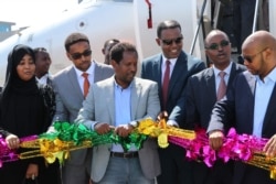 FILE - Abdirahman Omar Osman, center, and others celebrate after the first commercial flight by National Airways linking Addis Ababa to Mogadishu in 41 years landed in Mogadishu, Oct. 13, 2018. Mogadishu's mayor died Aug. 1.