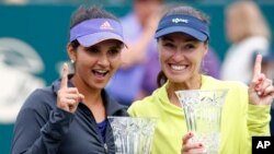 Sania Mirza (kiri) dan pasangan gandanya, Martina Hingis, dari Swiss dengan trofi mereka dari turnamen Family Circle Cup (12/4) di Charleston, South Carolina. (AP/Mic Smith)