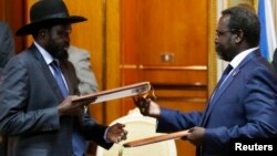 FILE - South Sudan's President Salva Kiir (L) and the country's rebel leader, Riek Machar, exchange signed peace agreement documents in Addis Ababa May 9, 2014.