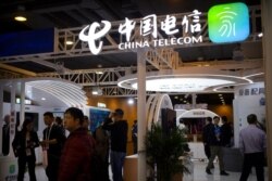 FILE - Visitors look at a display from Chinese telecommunications firm China Telecom at the PT Expo in Beijing, Oct. 31, 2019.