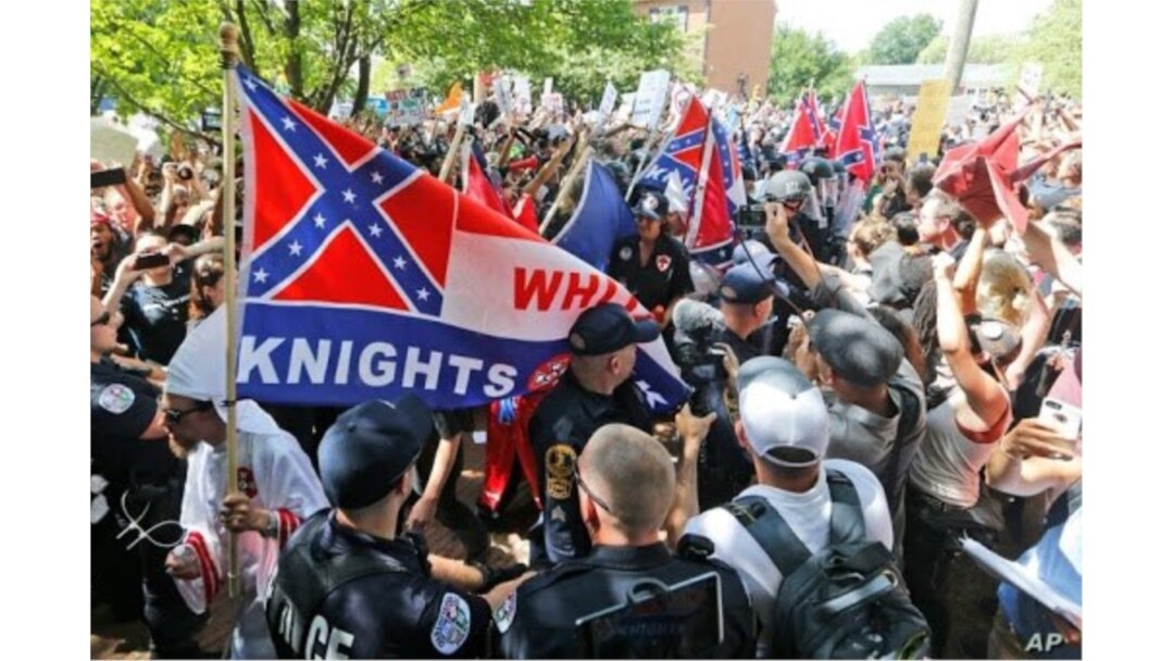Miembros de la supremacía blanca KKK son escoltados por la policía frente a un gran grupo de manifestantes durante una manifestación del KKK en Charlottesville, Virginia, el 8 de julio de 2017.
