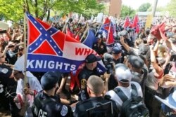 Miembros de la supremacía blanca KKK son escoltados por la policía frente a un gran grupo de manifestantes durante una manifestación del KKK en Charlottesville, Virginia, el 8 de julio de 2017.