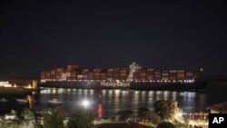 A cargo ship sails through the town of Suez, Egypt, March 30, 2021 as traffic resumed through the Suez canal after it was blocked by a massive ship that had been stuck sideways for nearly a week. 